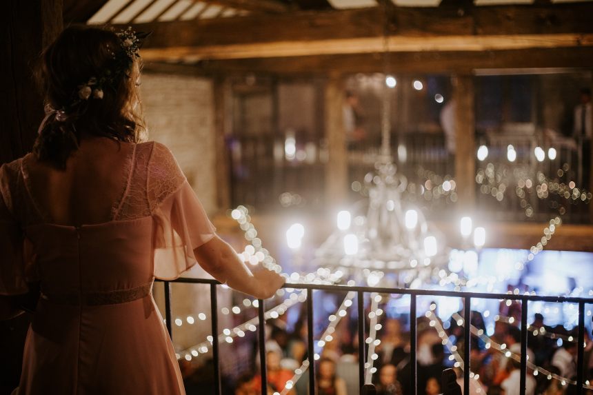 Bride looking down from balcony at wedding reception guests